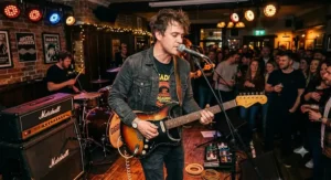 A left-handed guitarist playing a sunburst finish gigging electric guitar during a live music concert.