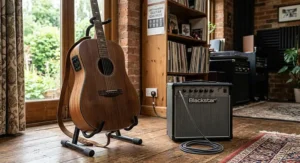 An electro-acoustic left-handed guitar resting on a stand next to an amplifier.