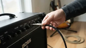 Beginner plugging an electric guitar cable into a simple solid-state amp for beginners